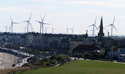 Skyline of town with wind turbines in background.
