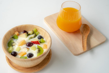 Fruit salad with yogurt on a wooden bowl and orange juice