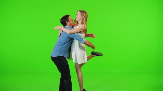 A in love man and a woman running to each other, hugging and spinning happily in slow motion over a green screen.