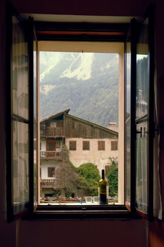 Fototapeta a bottle of wine and 2 glasses on the windowsill of the open window.