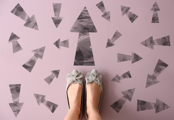 Woman standing on color background with arrows pointing in different directions. Concept of choice