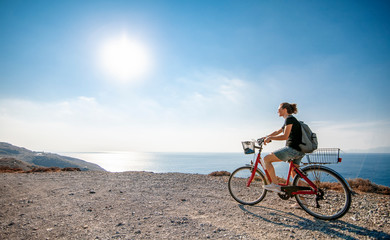 Fototapeta na wymiar Young beautiful girl woman travels by bicycle on a mountain landscape on the beach in the sun, tourism and leisure concept, Greece, Kos