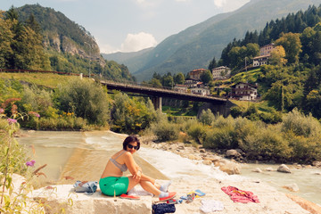 Fototapeta na wymiar woman sunbathing on a mountain river in the summer on a clear day.