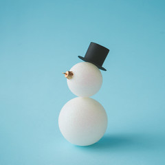Snowman made of Christmas bauble decoration on pastel blue background. Creative winter concept.