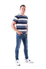 Happy successful young adult man with hands in jeans pockets smiling and looking at camera. Full body isolated on white background. 