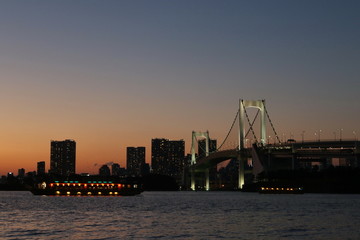 Obraz premium View from Odaiba Beach to Tokyo Bay with Rainbow Bridge at dusk, Tokyo, Japan