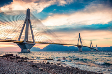 Obraz premium Dramatic evening scene with Rion-Antirion Bridge. Colorful spring scene of the Gulf of Corinth, Greece, Europe. Beauty of countryside concept background. Artistic style post processed photo.