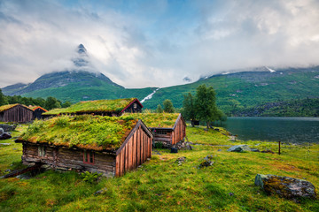 Norwegian typical grass roof wooden old house on the Innerdalsvatna lake. Colorful morning scene in Norway, Europe. Beauty of countryside concept background.