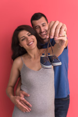 Naklejka premium young pregnant couple holding newborn baby shoes