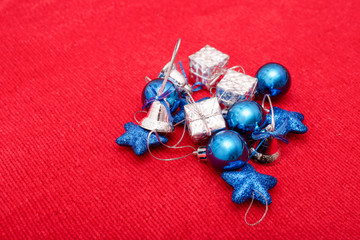 Christmas toys of blue and silver colors on red knitted fabric background