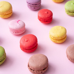 Fototapeta na wymiar Pastel pink table top with colorful macarons pattern. Minimal sweet food concept. Cookie concept.