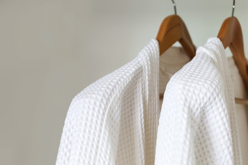 white bathrobe hanging on rack - obrazy, fototapety, plakaty