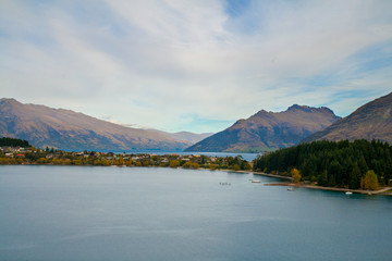 Queenstown New Zealand scenic view lookout with houses on lake Wakatipu, lakefront neighbourhood and holiday cottages, mountains of Central Otago around