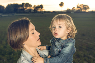 Close-up of a mother hugging her little daughter at sunset