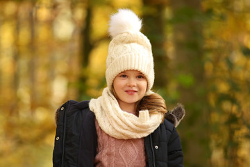 Kleines Mädchen in warmer Kleidung steht im Wald und lacht 