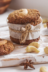 Homemade nutty vegan cinnamon cookies on white beige wooden board, close-up, natural light