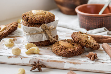 Homemade nutty vegan cinnamon cookies on white beige wooden board, close-up, natural light