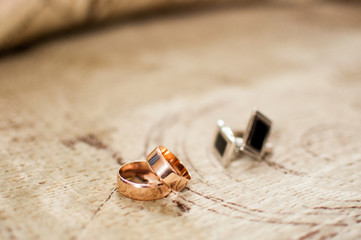 Gold wedding rings and cuff link on the wooden table