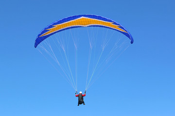 Paraglider flying in a blue sky