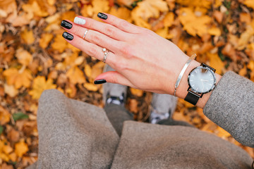 Woman hand with beautiful black manicure with design standing on the fall leaves background.