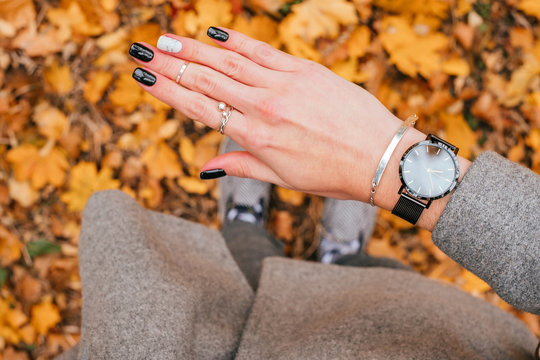 Woman Hand With Beautiful Black Manicure With Design Standing On The Fall Leaves Background.