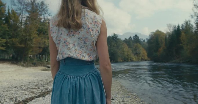 Young woman walking by river in forest