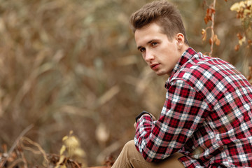 Handsome young guy in nature on an autumn day