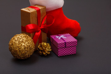 Gift boxes, Santa's boot, christmas ball and cone on black background