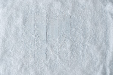 White wooden table background with snow. Winter or Christmas top view. Minimal flat lay.