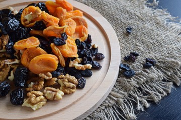Useful dried fruits and walnuts on wooden background and burlap.