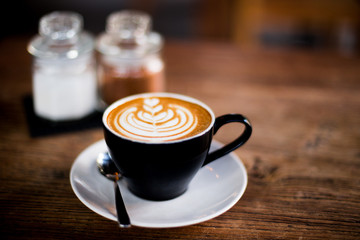 cup of cappuccino with art latte on wooden table background