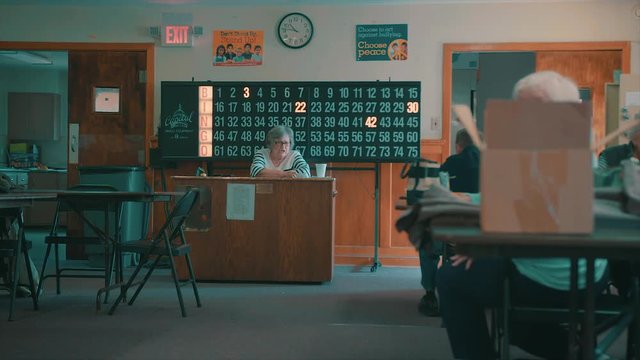 Slow-motion clip of an elderly women running a quiet bingo hall.