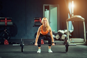 Fototapeta na wymiar Girl in gym doing squats with barbell