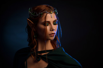 Close up of gorgeous girl in emerald cloak hiding her eyes.