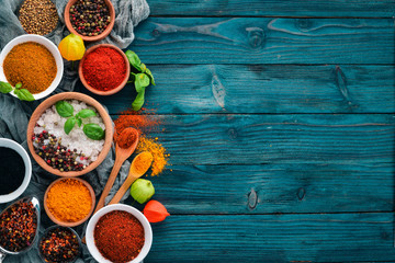Spices and herbs on a blue wooden table. Basil, pepper, saffron, spices. Indian traditional cuisine. Top view. Free copy space. © Yaruniv-Studio