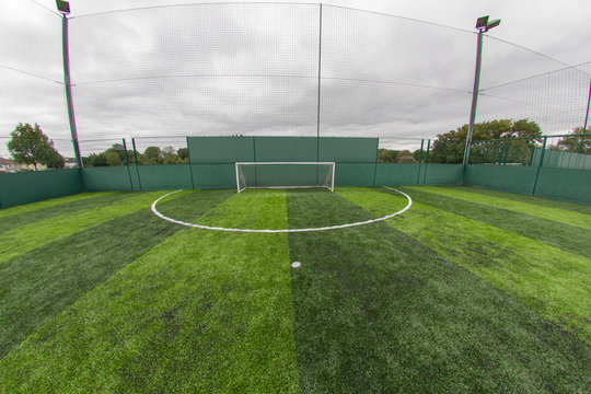 Football goal posts and football stripy green pitch, wide angle photo.