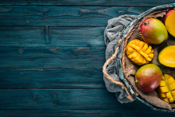 Fresh mango in a wooden box. On a wooden background. Tropical Fruits. Top view. Free copy space.