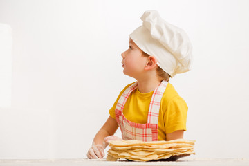 Child chef cook and Stack of homemade whole wheat flour tortilla on wooden table