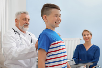 Doctor looking at posture of boy in private clinic.