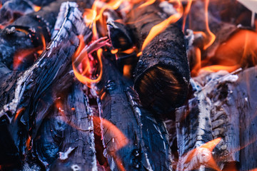 Bright hot coals and burning woods in bbq grill pit. Glowing and flaming charcoal, barbecue, red fire and ash.