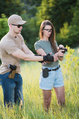 the instructor teaches the girl to shoot a pistol at the range
