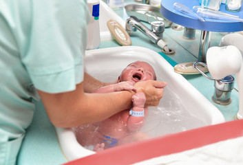 A nurse gives the first bath of a newborn boy