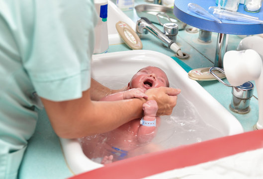 A nurse gives the first bath of a newborn boy