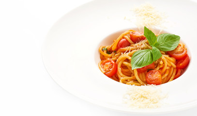 Classic spaghetti with cherry tomatoes and parmesan cheese decorated with basil on white plate