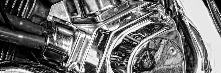 A panoramic photo of fragment of a motorcycle with chrome elements reflecting another motorcycle