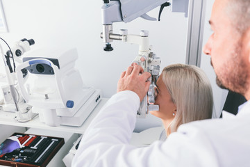 Optitian testing his patient's eyesight.