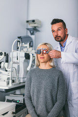 Optician checking patient's eyesight with trial frame.