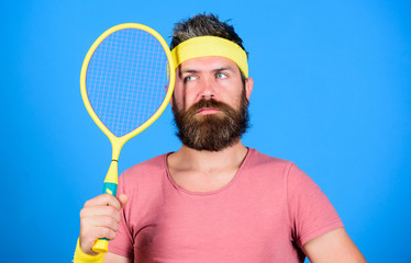 Tennis club concept. Man bearded hipster wear old school sport outfit with bandages. Tennis player retro fashion. Tennis sport and entertainment. Athlete hold tennis racket in hand on blue background