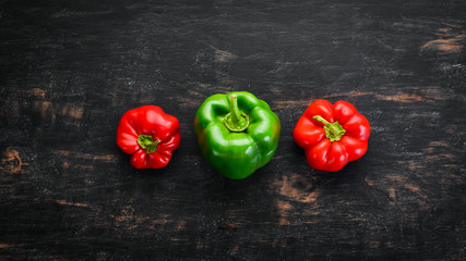 Red and green pepper. Top view. On a black wooden background. Free copy space.