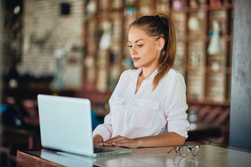 Businesswoman sitting in restaurant and using laptop. Hands on keyboard.